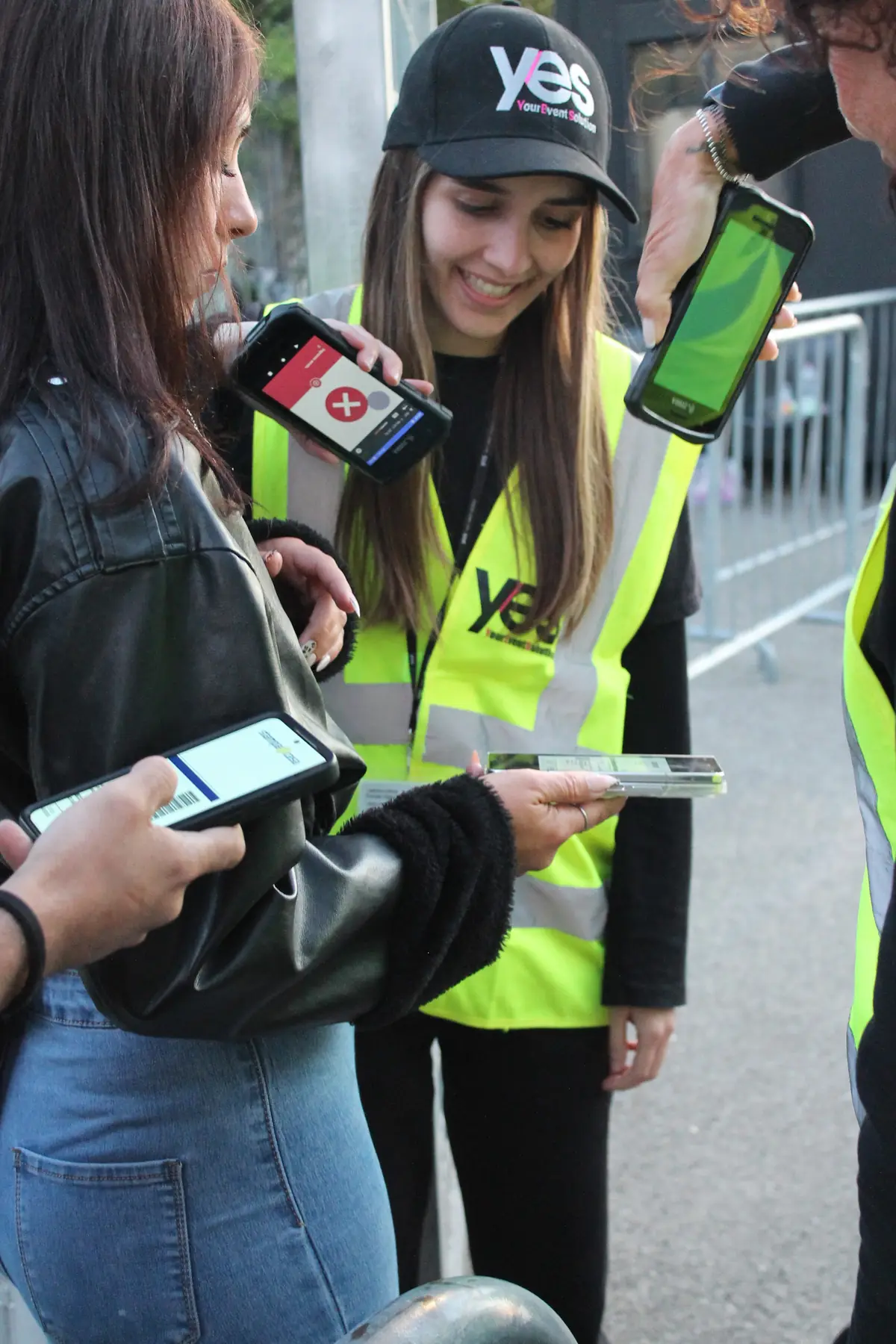 Un'operatrice YES con cappellino e pettorina controlla i biglietti sullo smartphone degli spettatori all'ingresso