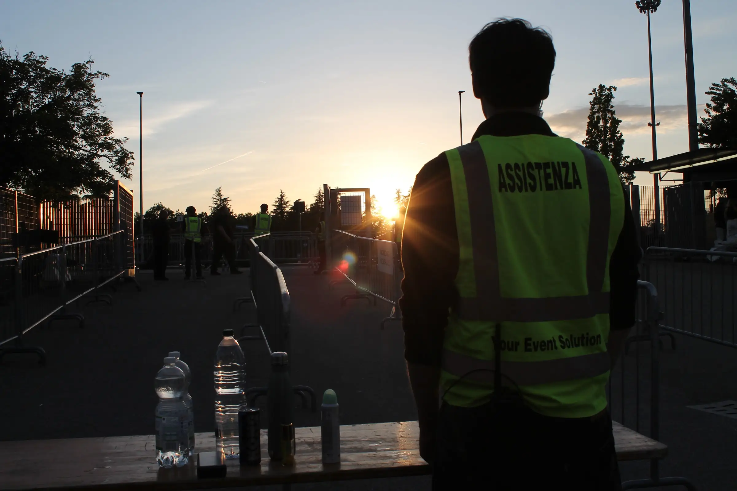 Uno steward YES con la pettorina Assistenza, di spalle, presidia il varco d'ingresso al tramonto